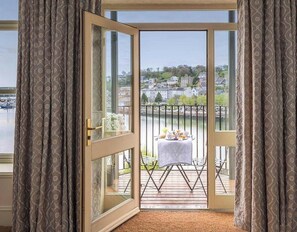 Een balkon met een tafel en stoelen, met uitzicht op een waterpartij en een stad.