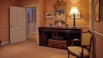 A hallway with a wooden desk, a lamp, a chair, and a door.