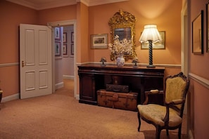 A hallway with a wooden desk, a lamp, a chair, and a door. - The Secret Garden (Kinsale)