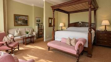 A bedroom with a four-poster bed, a sofa, a chair, and a desk.