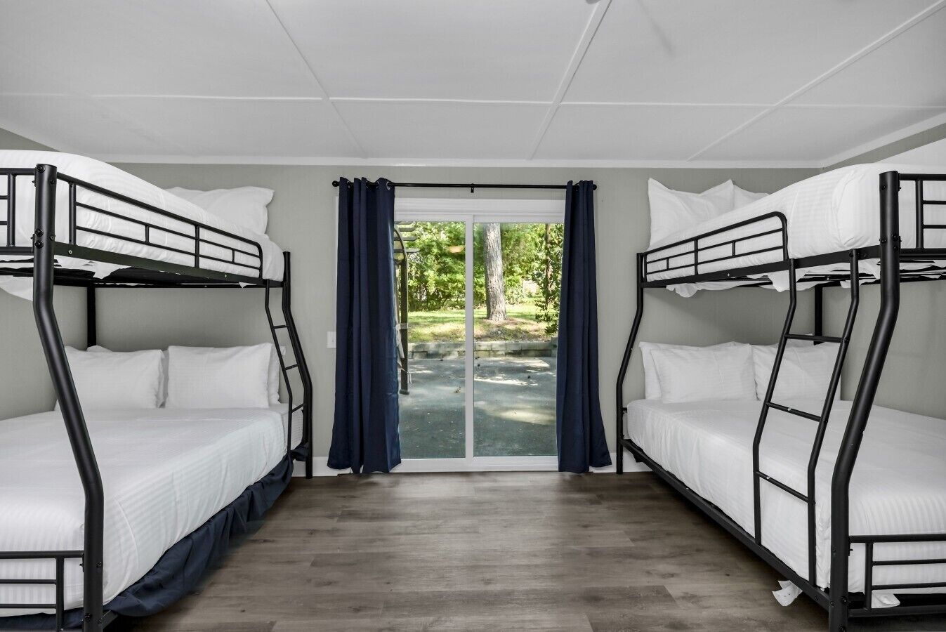 Une chambre avec des lits superposés, une porte-fenêtre coulissante donnant sur un espace extérieur et un plancher en bois.