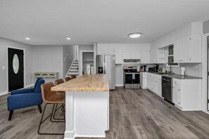 Eine moderne Küche mit weißen Schränken, einer Holzinsel und einem eingebauten Backofen.