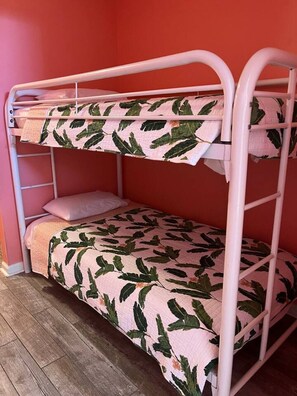 Ein Etagenbett mit einem Bettbezug mit Blättermotiv und einer linken Leiter.