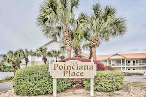 En skylt med texten ”320 Poinciana Place”, och en byggnad syns i bakgrunden.