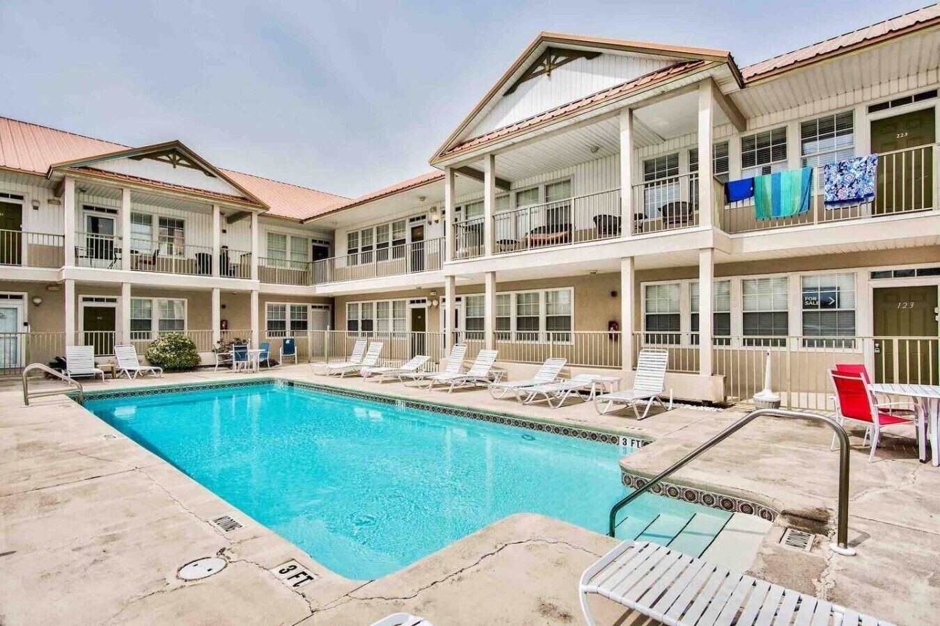 A multi-story hotel with a swimming pool, outdoor seating, and balconies.