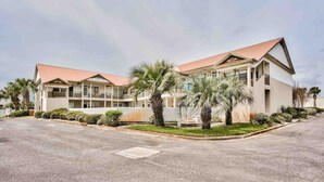A two-story hotel with a red roof, multiple balconies, and a well-maintained lawn with palm trees. - 124 Seashell Cove Poinciana Place (Miramar Beach)