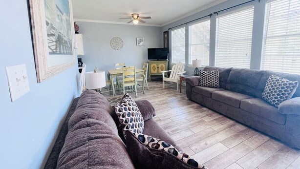 A living room with a sofa, a couch, a dining table, and chairs. - 124 Seashell Cove Poinciana Place (Miramar Beach)