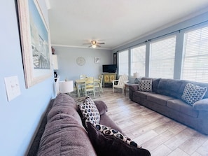 A living room with a sofa, a couch, a dining table, and chairs. - 124 Seashell Cove Poinciana Place (Miramar Beach)