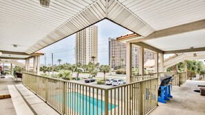 Ein überdachter Außenbereich mit Pool, Geländer und Blick auf hohe Gebäude im Hintergrund.