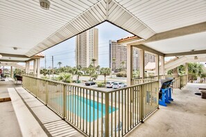 Un espacio al aire libre cubierto con piscina, barandilla y vista a edificios altos al fondo.