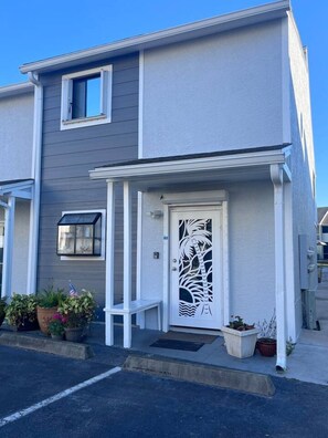 A two-story residential building with a white exterior, a front porch, and a decorative door with a palm tree design. - 103 Siren Cove Misty Cove (Destin)