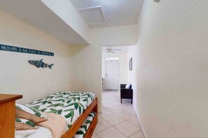 Una camera da letto con un letto, un comodino, una decorazione a forma di pesce appesa al muro e una porta che dà su un'altra stanza.