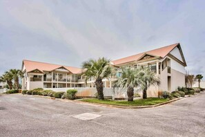 A two-story hotel with a red roof, multiple balconies, and palm trees in the front yard. - 214 Dolphin Cove Poinciana Place (Miramar Beach)
