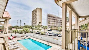 A hotel balcony with a pool, lounge chairs, and a view of tall buildings and parked cars. - 214 Dolphin Cove Poinciana Place (Miramar Beach)