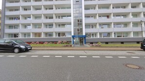 Un hôtel à plusieurs étages doté d’une entrée principale, de balcons à chaque étage et d’un espace de stationnement à l’avant.