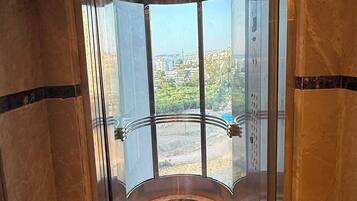 A glass elevator with a marble floor and a city view.