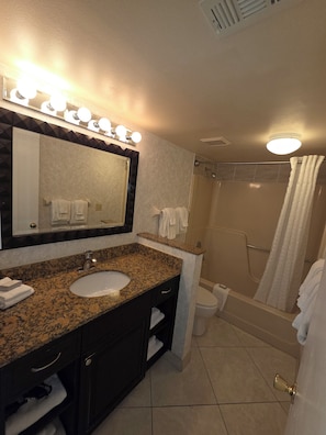 A bathroom with a granite countertop sink, a mirror with lights, a shower, and a toilet. - 1BR Villa Near Disney Pool & Resort Amenities (Kissimmee)