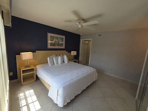 A hotel room with a bed, two bedside tables, a ceiling fan, a door, and a wall-mounted picture. - 1BR Villa Near Disney Pool & Resort Amenities (Kissimmee)