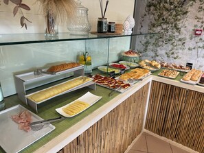 Buffet com diversos alimentos, incluindo massas, pastéis e carnes.