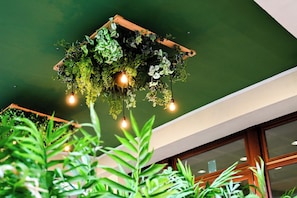 A ceiling with a hanging planter filled with various green plants and three exposed bulbs. - Hotiday Bibbona Beach (Marina di Bibbona)