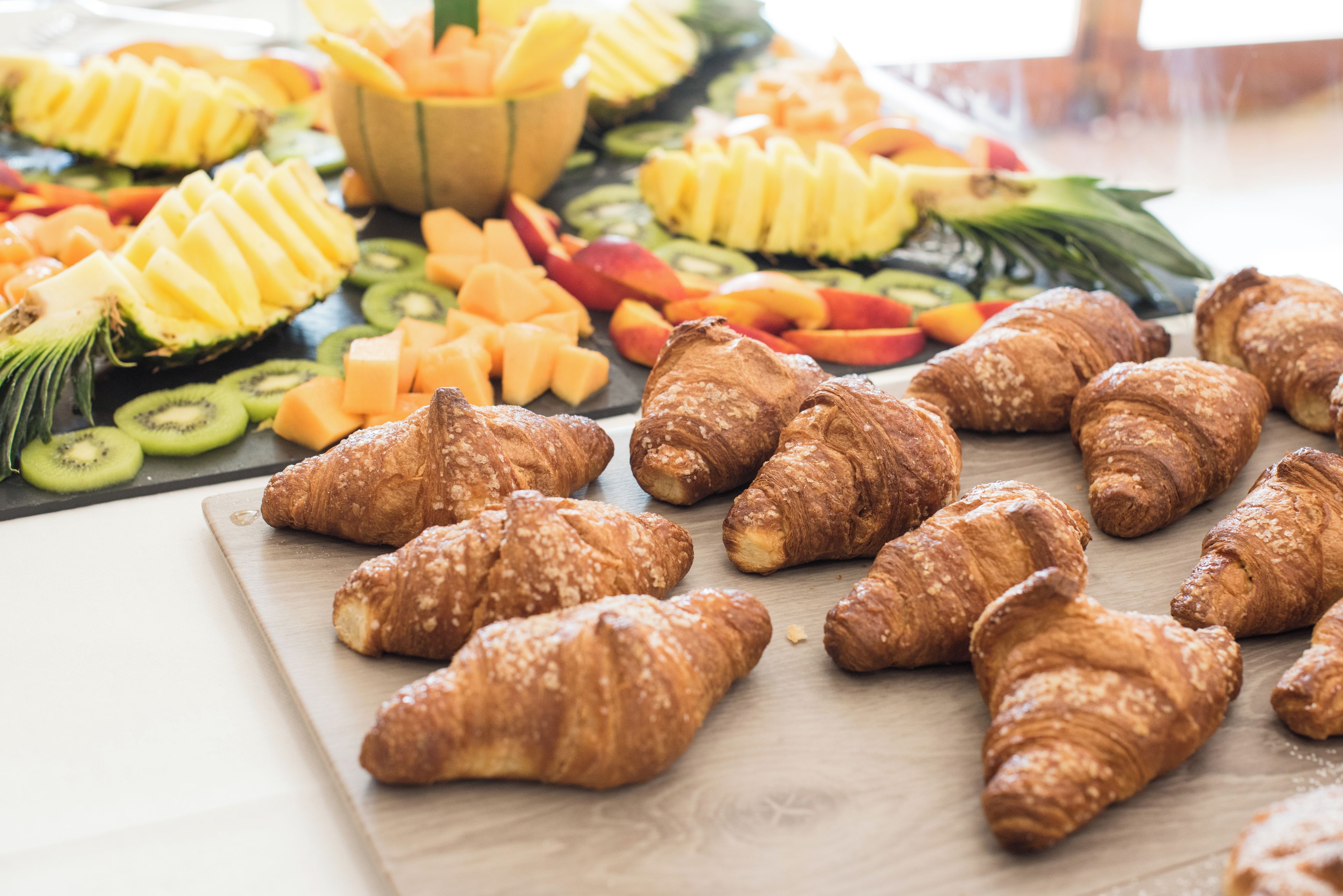 Un tavolo con frutta varia e croissant.