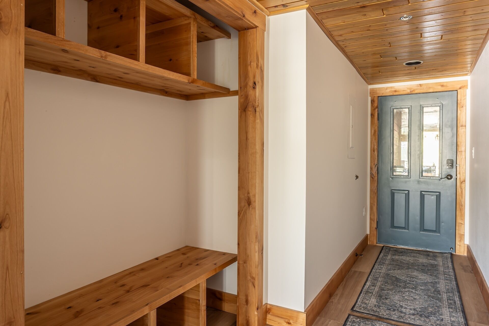 A hallway with wooden beams, a blue door, and a wooden bench.