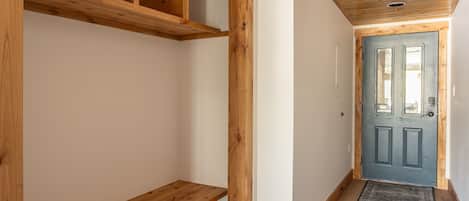 A hallway with wooden beams, a blue door, and a wooden bench.