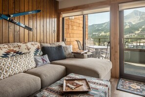 A cozy living room with a sofa, pillows, and a tray on a rug. - Mtn Views | Free Shuttle | Fireplace (Big Sky)