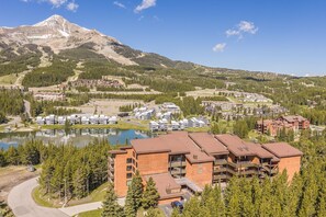 A resort with multiple buildings, a lake, and a mountain in the background. - Mtn Views | Free Shuttle | Fireplace (Big Sky)