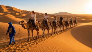 Un grupo de personas montando camellos en una duna de arena del desierto.