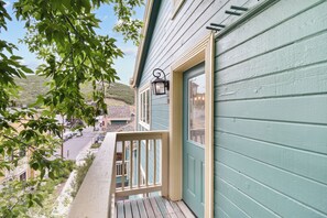 A wooden deck with a railing, a door with a window, and a street view in the background. - Walk to Main Street and Lift | Fireplace (Park City)