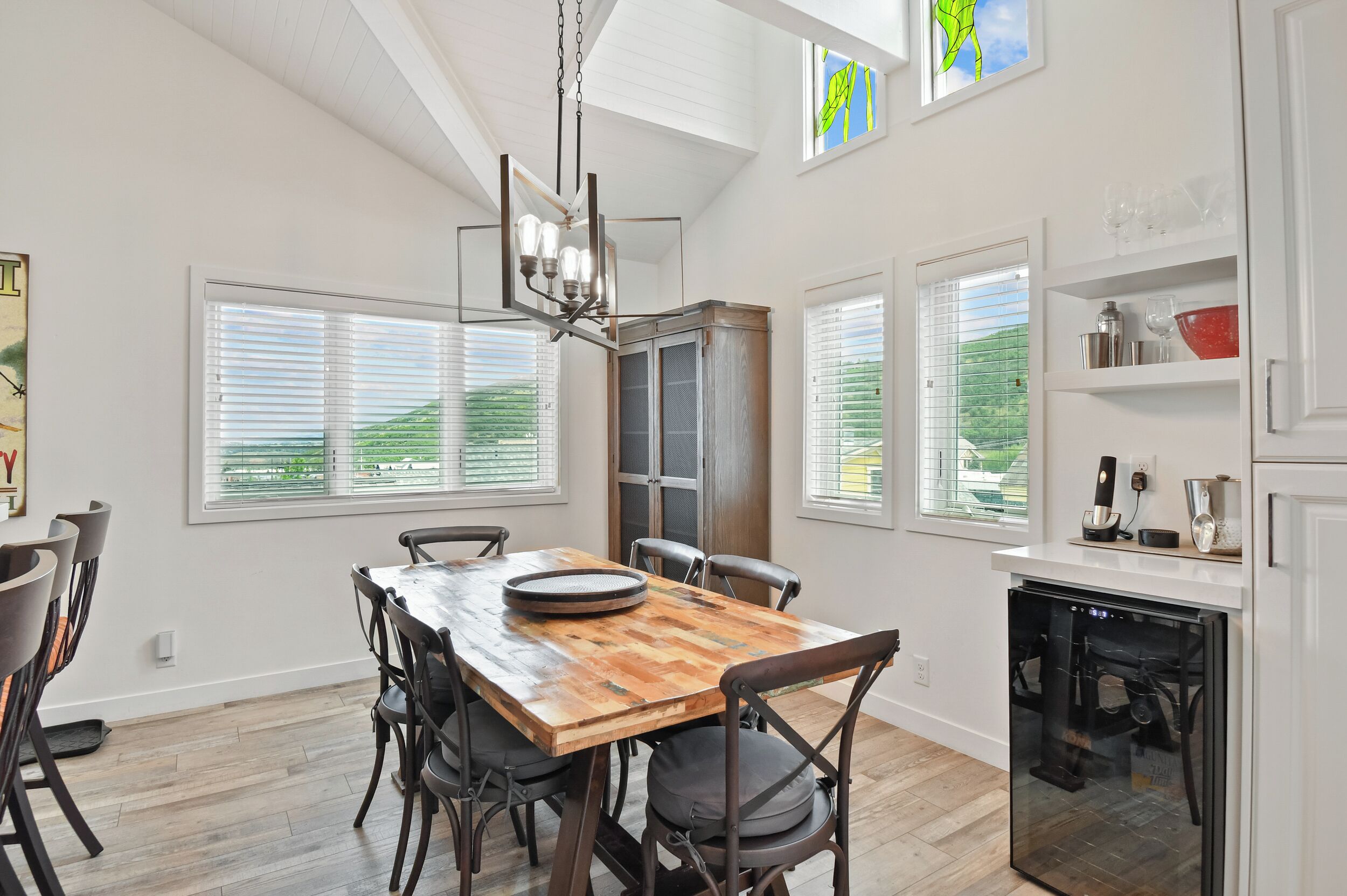 A modern kitchen with a wooden dining table, chairs, and a built-in oven.