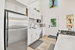A modern kitchen with white cabinets, stainless steel appliances, and a view of the outdoors through a window. - Walk to Main Street and Lift | Fireplace (Park City)