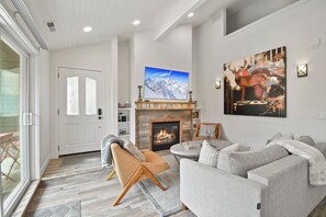 Ein modernes Wohnzimmer mit Kamin, einem darüber montierten Fernseher und einem großen abstrakten Gemälde an der Wand.