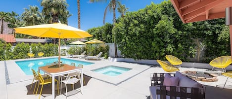 A pool area with lounge chairs, umbrellas, and a table.