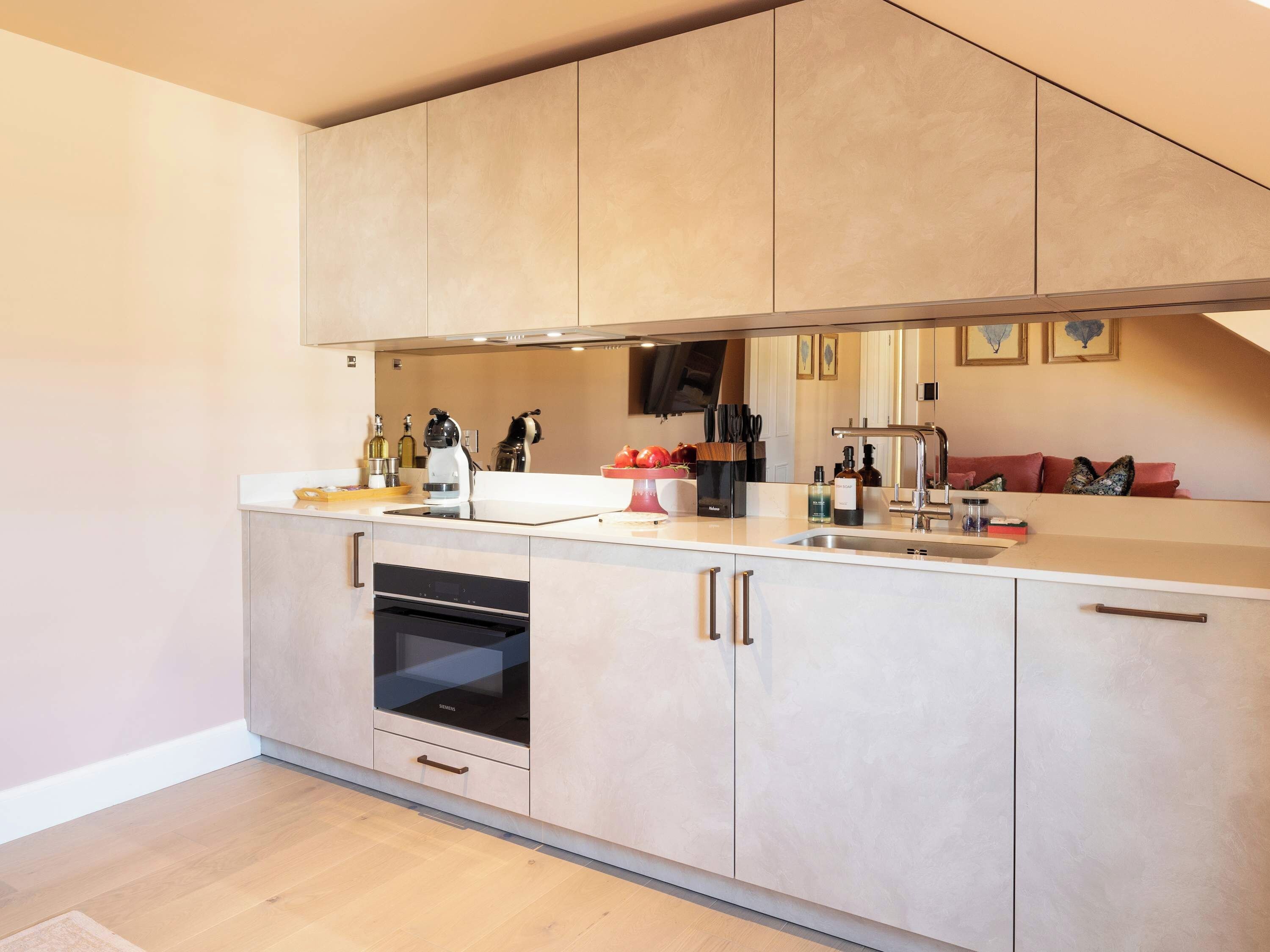 Een moderne keuken met een ingebouwde oven, een spoelbak en een aanrecht met diverse keukenbenodigdheden.
