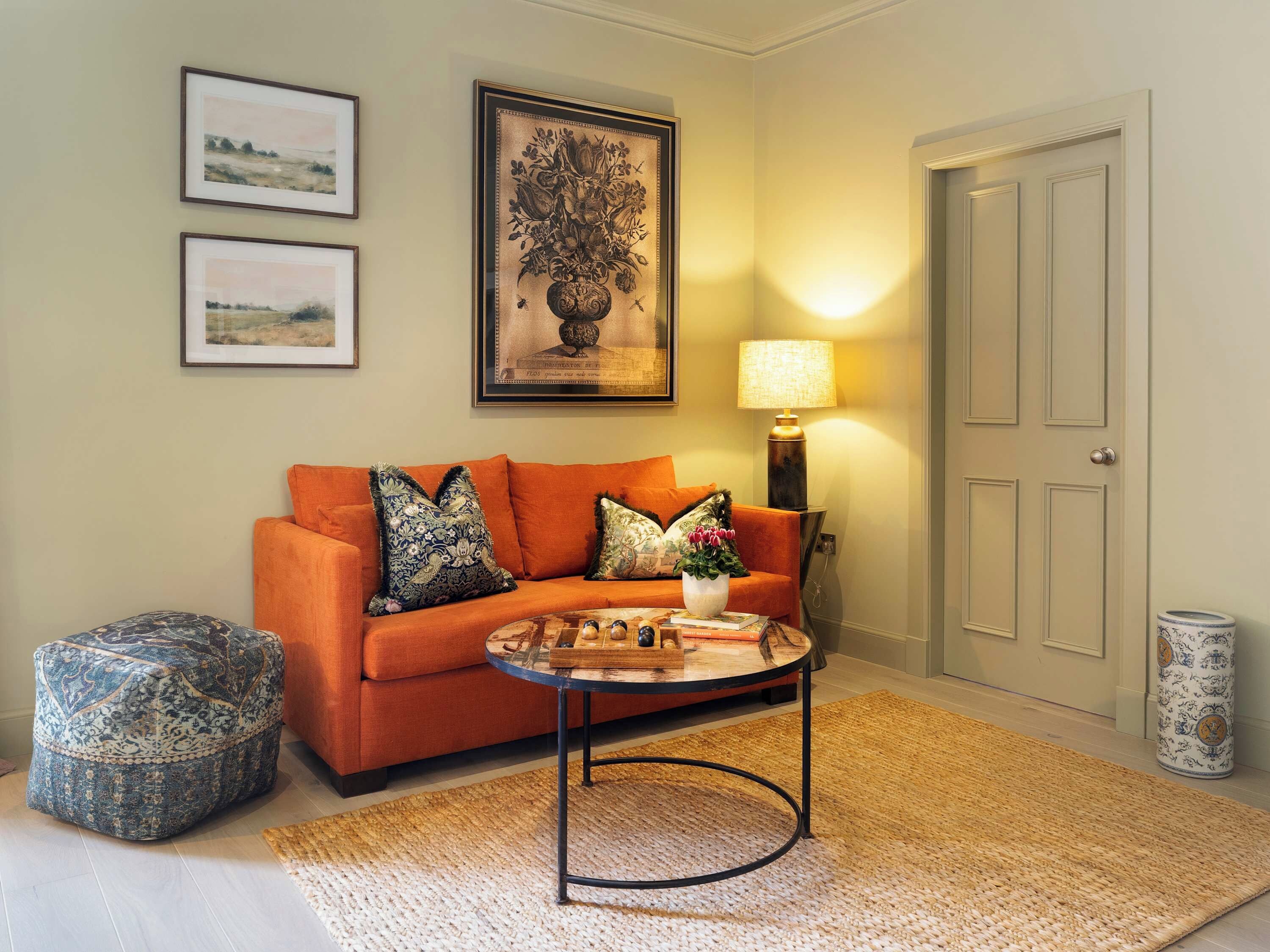 A living room with a sofa, ottoman, coffee table, and wall art.
