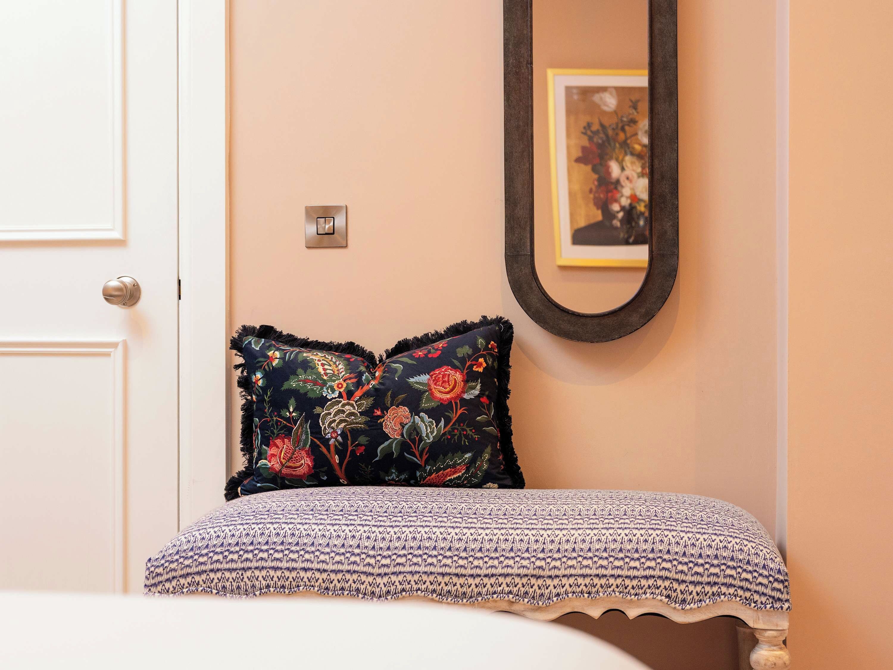 A bedroom with a bed, a door, a light switch, and a framed picture on the wall.