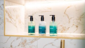 A marble wall with three bottles of Sea Kelp shampoo and conditioner on a shelf. - Pentland Suite - 1 bedroom accessible apartment at Hill Street (Edinburgh)