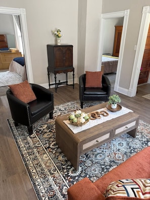 A living room with a sofa, armchair, coffee table, and a cabinet.