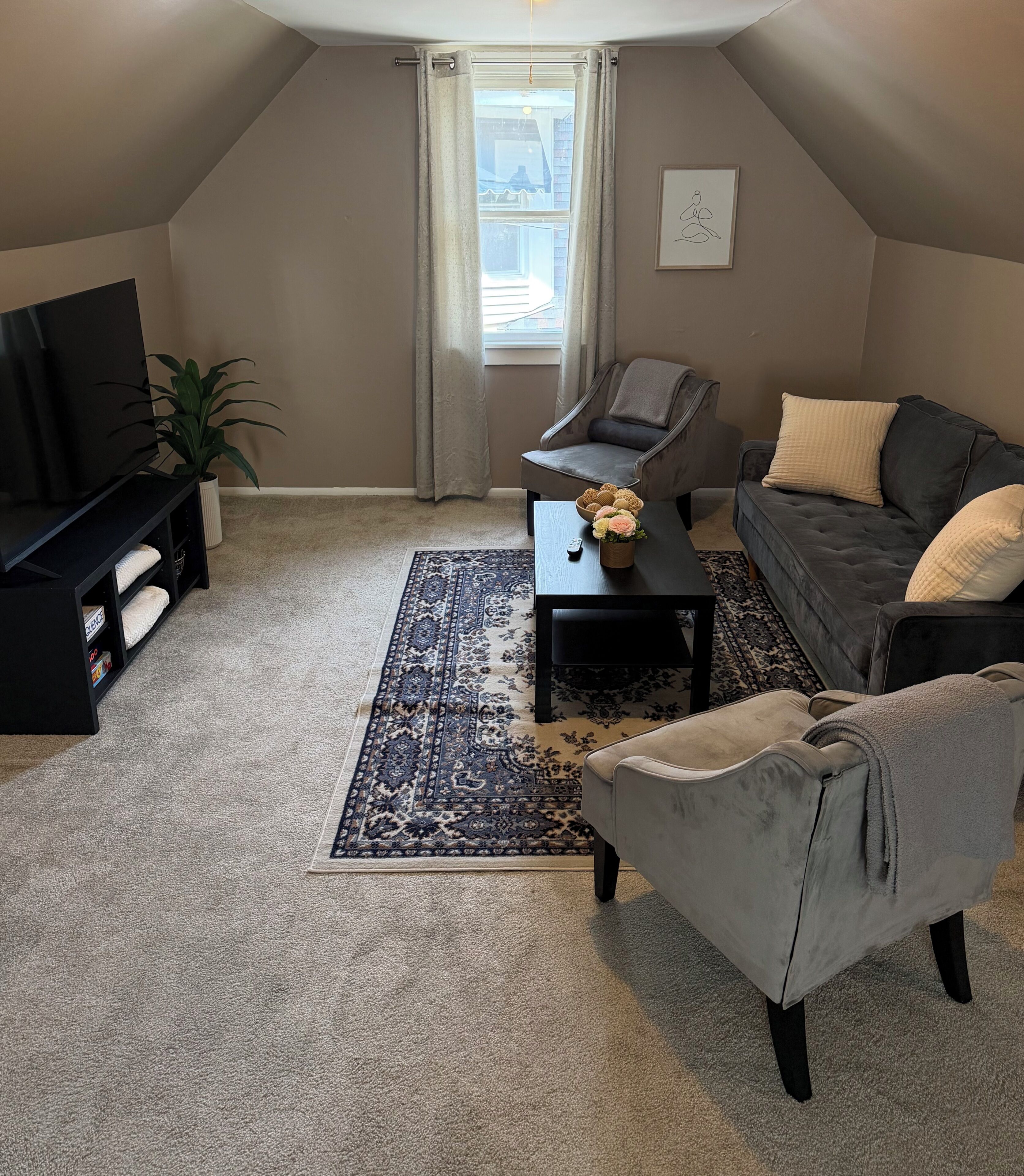 Un salon confortable avec un téléviseur à écran plat, un canapé, une table basse et un tapis à motifs.