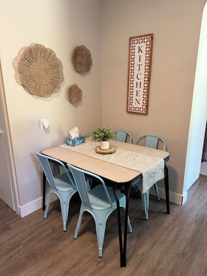 A dining area with a table, chairs, a potted plant, and wall decorations.