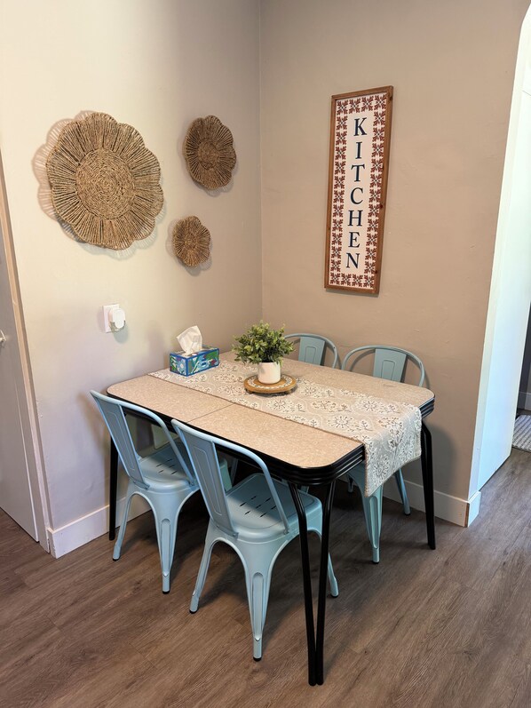 A dining area with a table, chairs, a potted plant, and wall decorations.