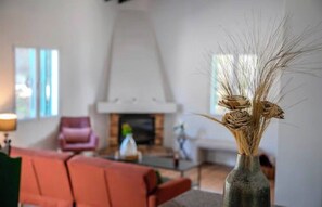 A living room with a fireplace, a sofa, and a vase with dried plants.