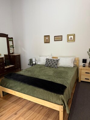 A neatly arranged bedroom with a bed, dresser, and bedside tables.