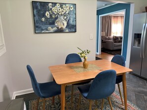 A dining area with a wooden table, four blue chairs, and a vase with flowers.