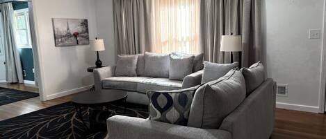A living room with a grey sofa, two side tables with lamps, a patterned rug, and a ceiling fan.