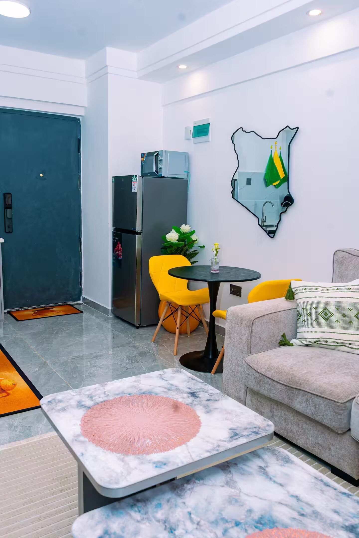 Un espacio habitable compacto con kitchenette, un comedor con mesa y sillas, un sofá y un adorno de pared.