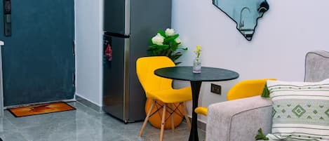 Un espacio habitable compacto con kitchenette, un comedor con mesa y sillas, un sofá y un adorno de pared.