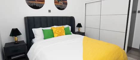 A bedroom with a bed, bedside tables, a wardrobe, and two wall-mounted circular mirrors.
